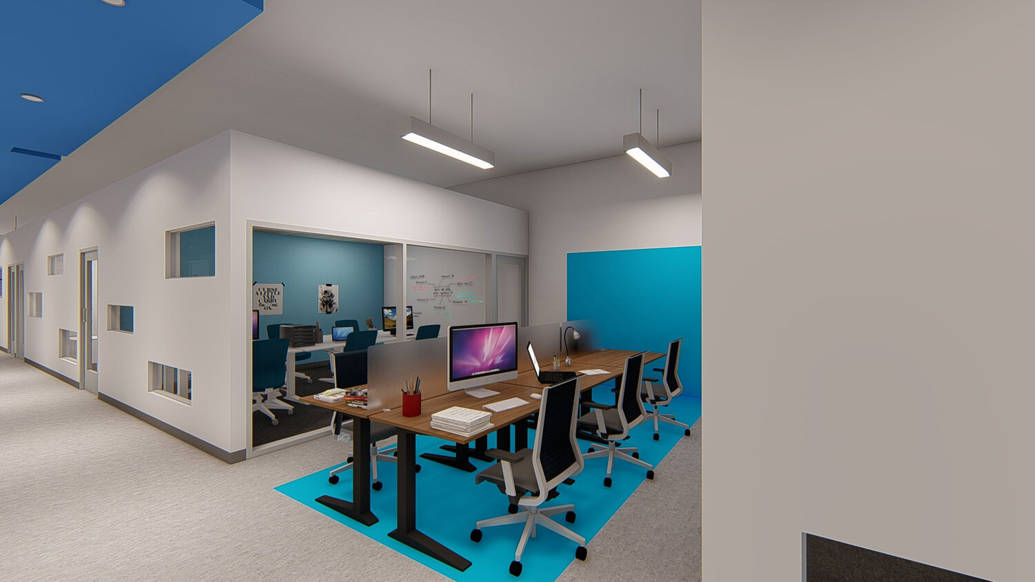 Office workspace with a wooden table, multiple chairs, computers, and a glass-walled meeting room in the background.