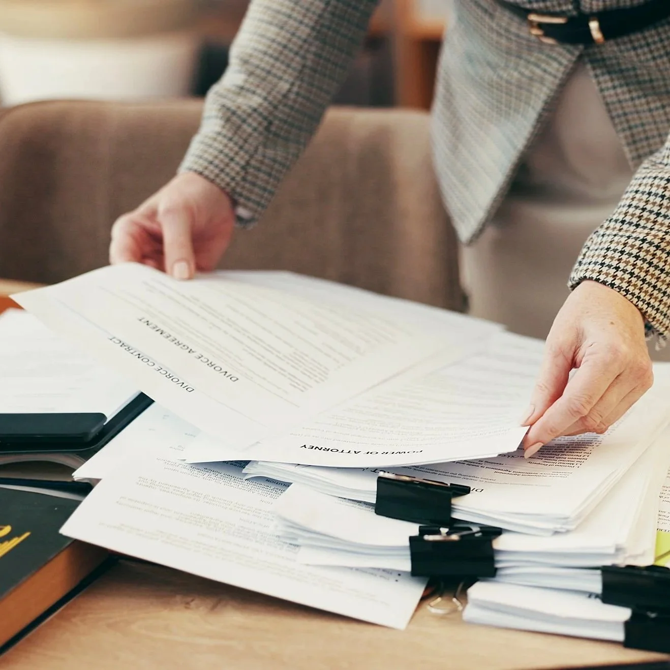 Person in business attire organizing and reviewing stacks of legal documents on a desk.