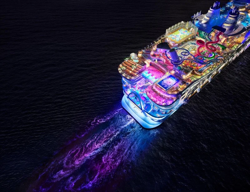 Crucero de lujo iluminado en el mar por la noche, con muchas áreas de recreación y piscinas en la cubierta.