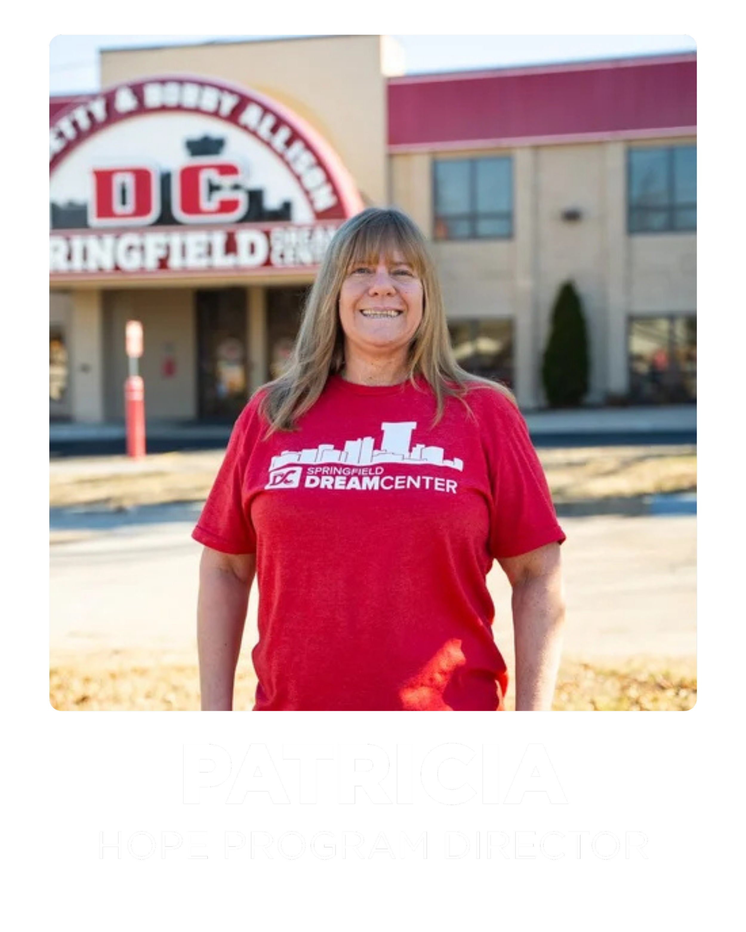 A woman with long blonde hair smiling and wearing a red t-shirt with a springfield skyline graphic and the text 'Springfield DC Dream Center.' She is standing outside in front of a building with the Springfield DC Dream Center sign visible in the background.
