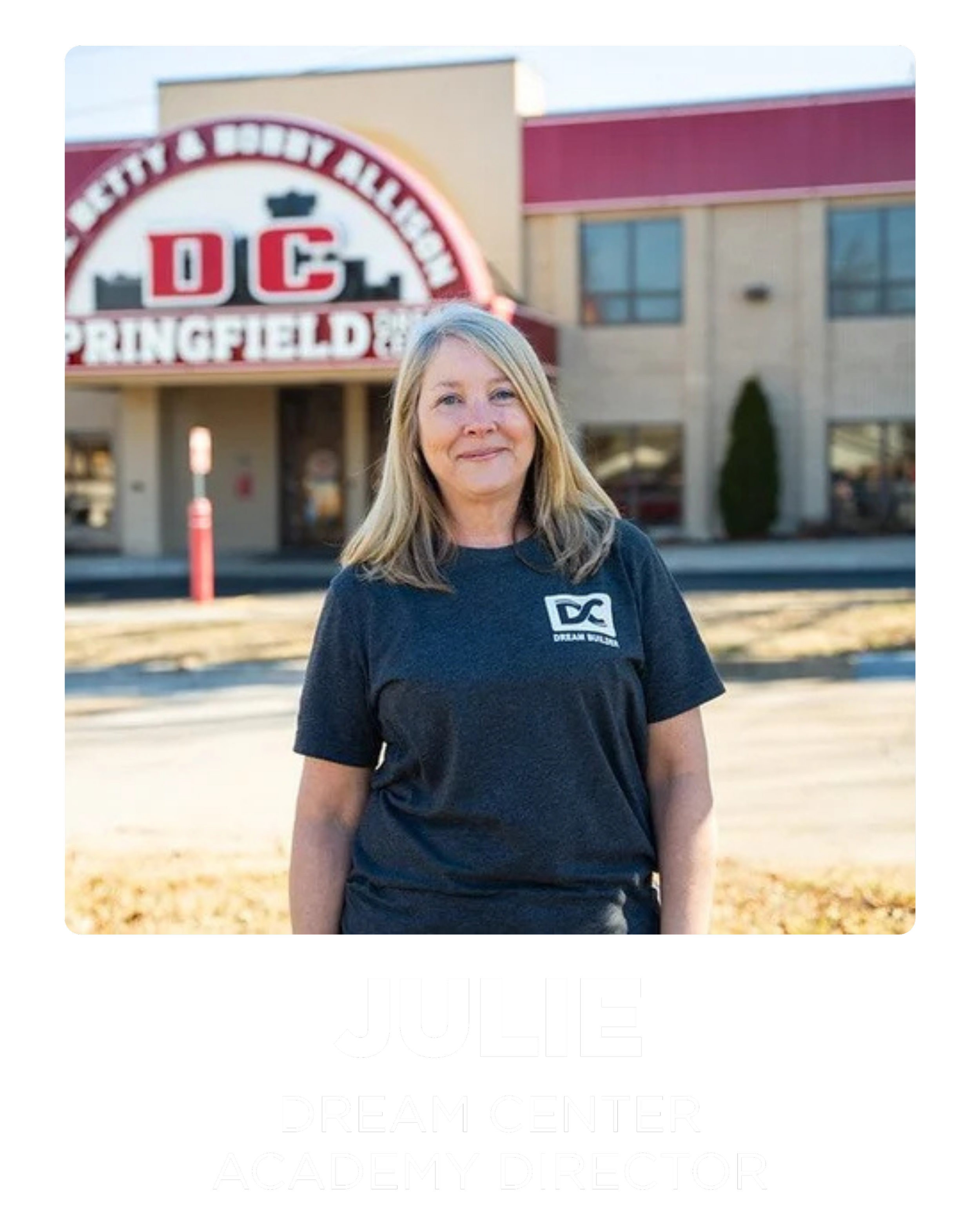 Portrait of Julie, a woman with blonde hair, standing outside a building with a sign that reads "Springfield" and "DC", wearing a dark t-shirt with a logo, labeled as "Dream Center Academy Director".