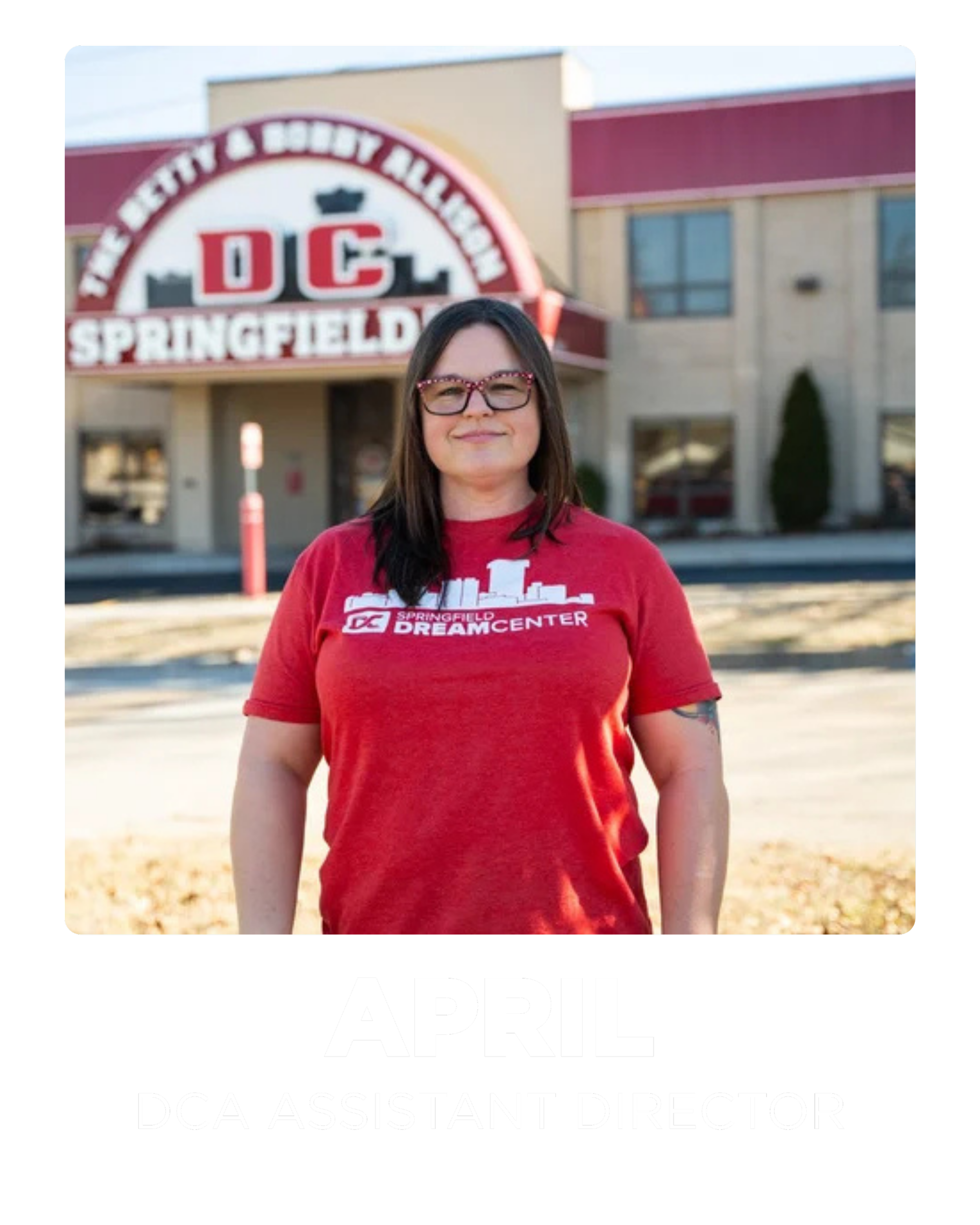 Portrait of a woman in a red Springfield DC Dream Center t-shirt standing outdoors in front of a building with a sign that reads Springfield and DC, with a banner below stating April DCA Assistant Director.