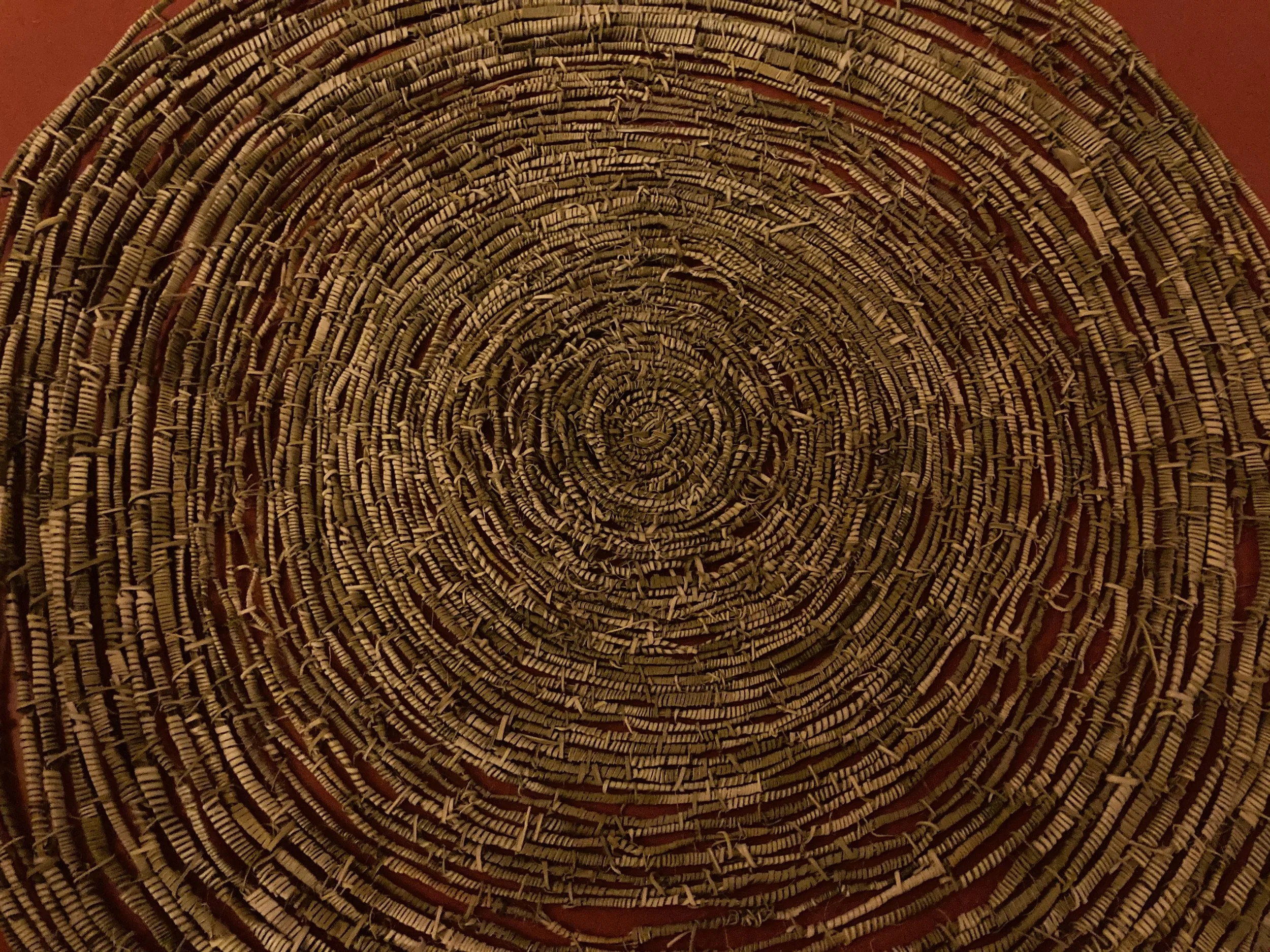 Close-up of a round woven wicker basket with concentric circular patterns.