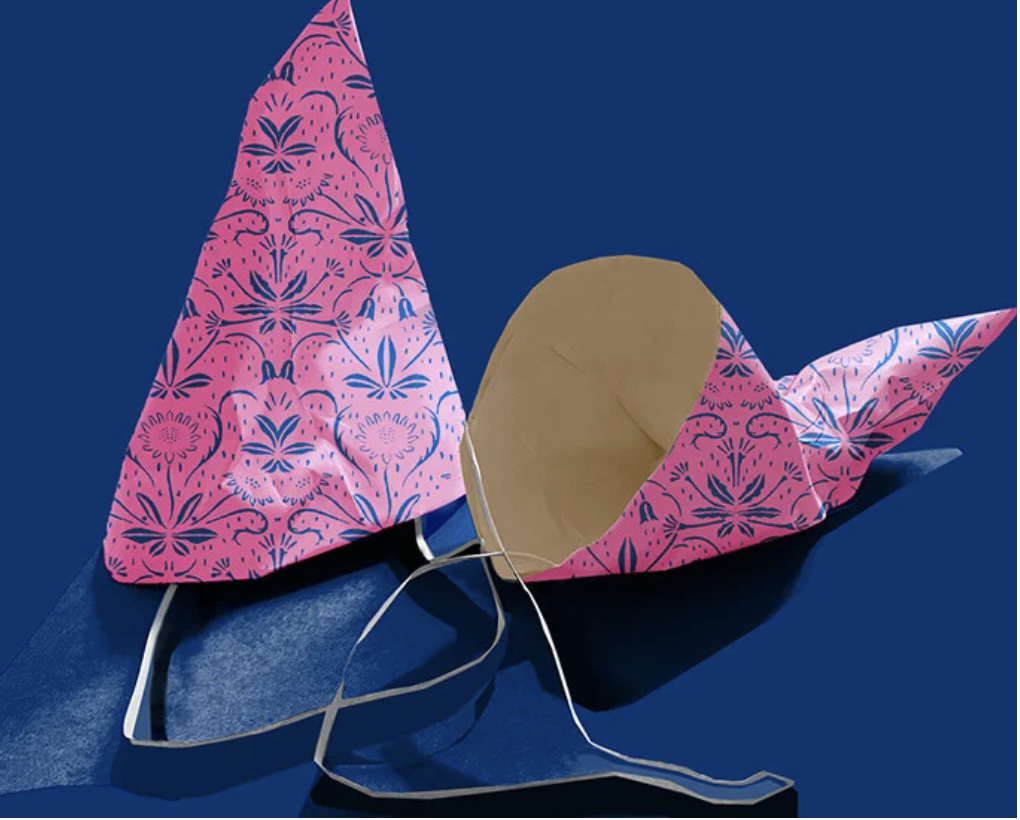 Paper craft butterfly with pink patterned wings and a cardboard body on a dark blue surface.