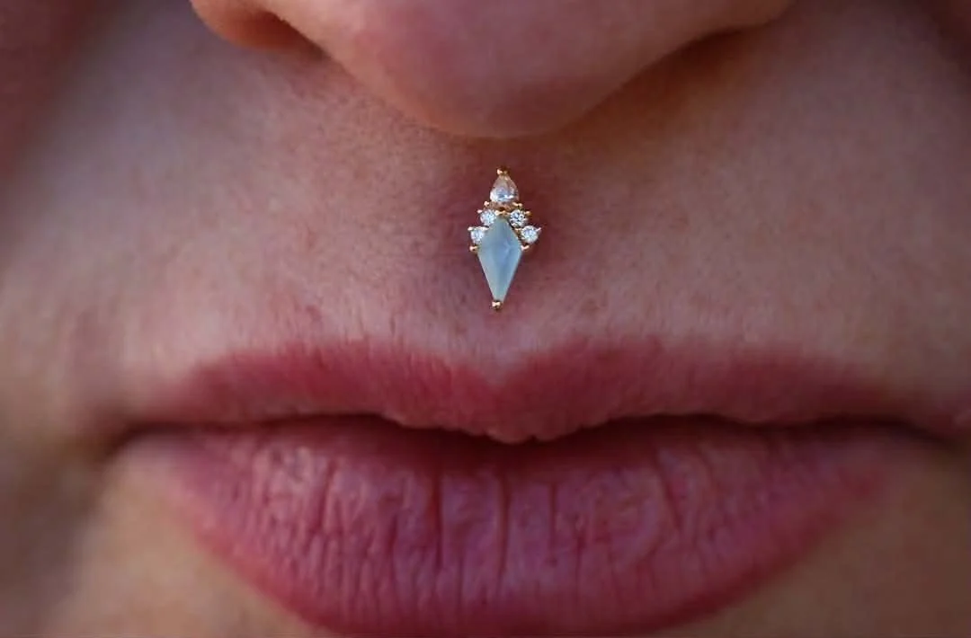 Philtrum piercing with a yellow gold Afterglow end featuring sandblasted Swiss blue topaz and white cubic zirconias from Buddha Jewelry