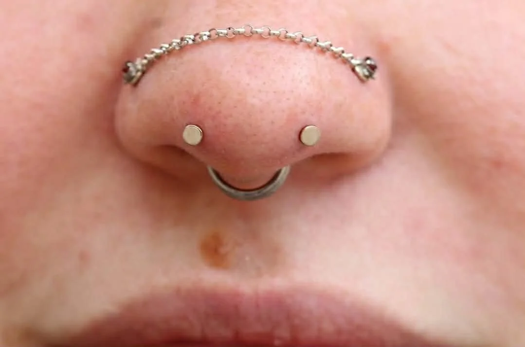 Mantis Piercing with 2.5mm white gold high polish discs
Healed paired nostrils with garnet and a white gold nose chain