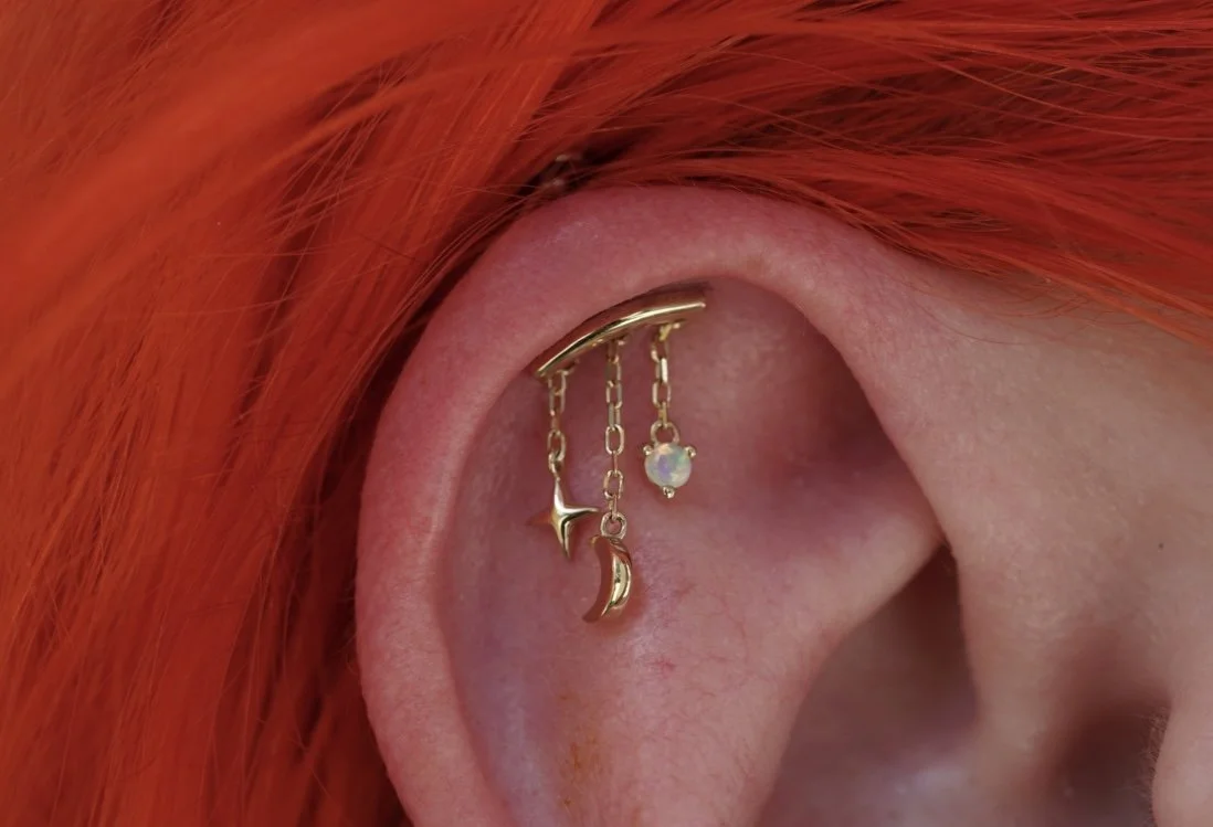 Helix piercing using a Cassiopeia in solid 14k yellow gold from Modern Mood with a genuine white opal