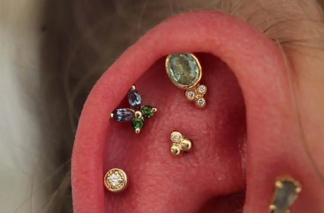Triple helix piercing featuring all yellow gold
Top - Oval Green Beryl with genuine diamonds from Modern Mood Jewelry
Middle - Monarch with lab created Alexandrite and green tourmaline BVLA Body Vision Los Angeles
Bottom - Millgrain bezel with genuin
