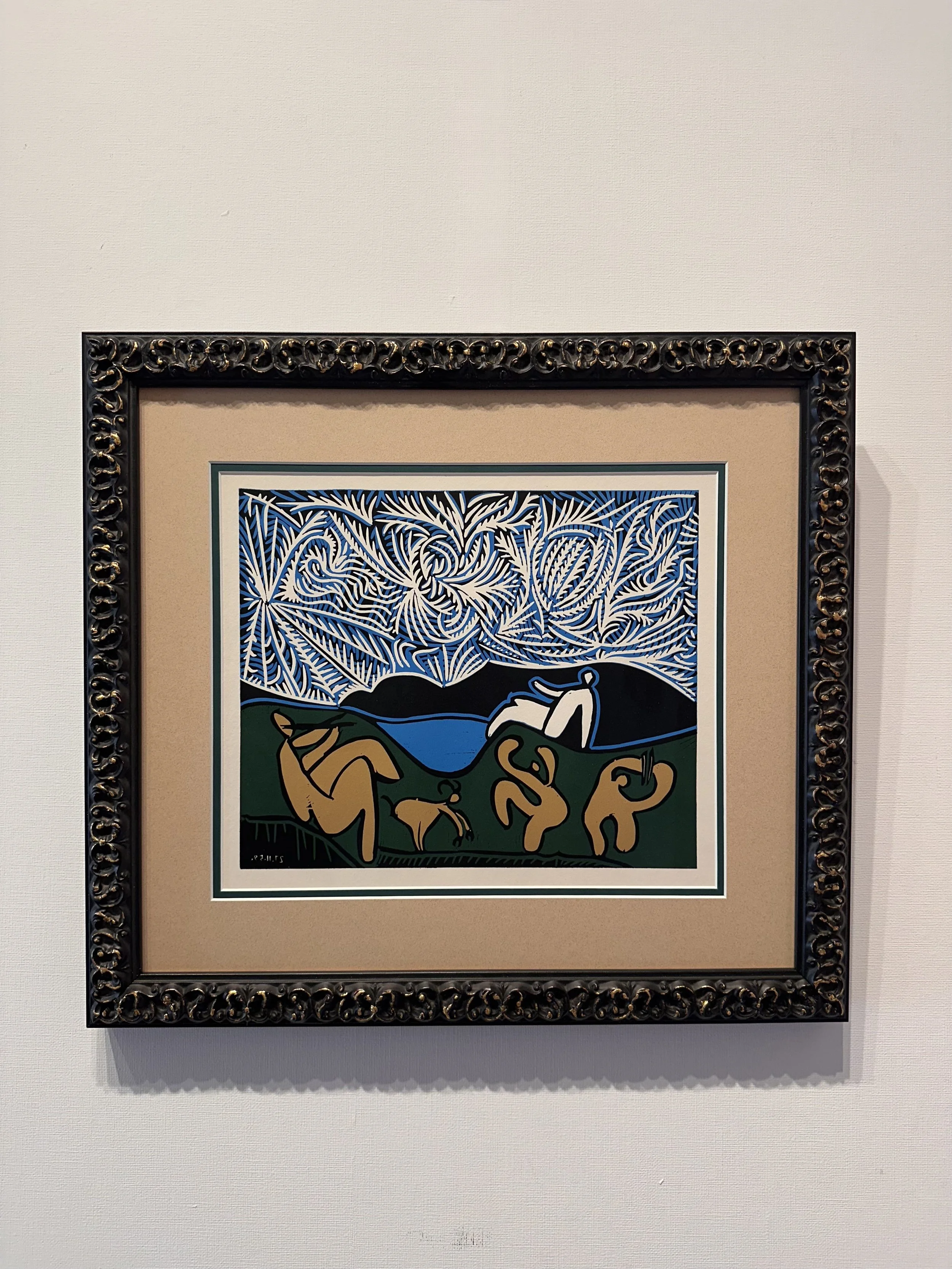 Framed artwork of a colorful landscape with stylized trees, mountains, a lake, and abstract figures and shapes, with a signature in the bottom left corner.