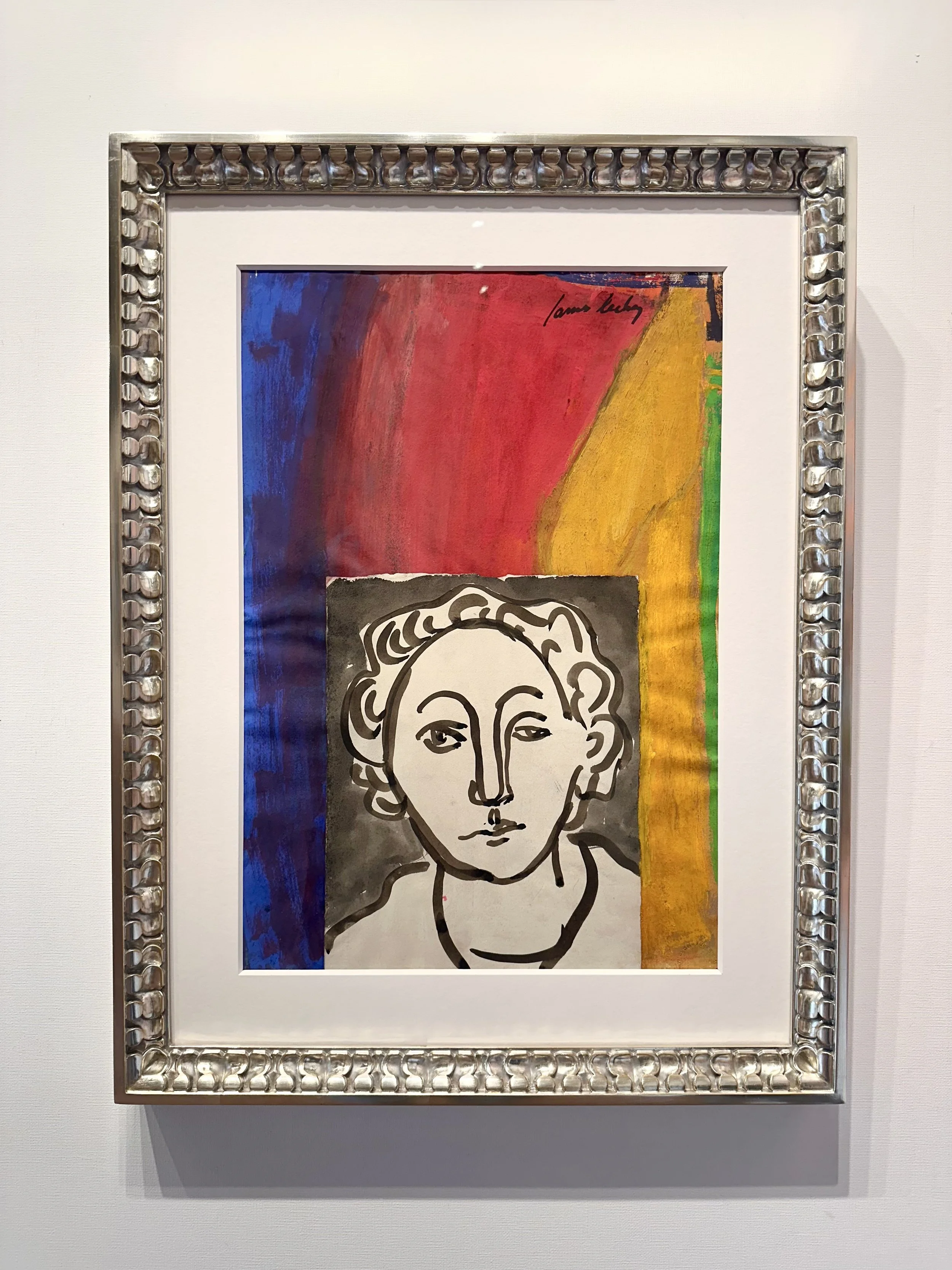 A framed abstract artwork featuring a black and white line drawing of a woman's face set against a colorful background with red, blue, yellow, and green sections.
