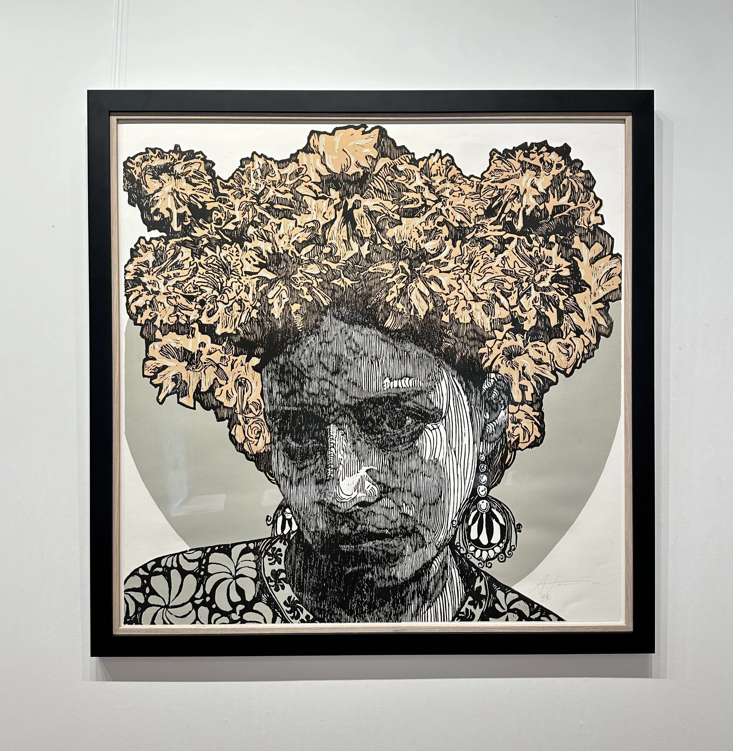 Framed artwork of a woman with large hair made of textured, floral-like shapes, wearing earrings and patterned clothing, with a monochrome face illustration.