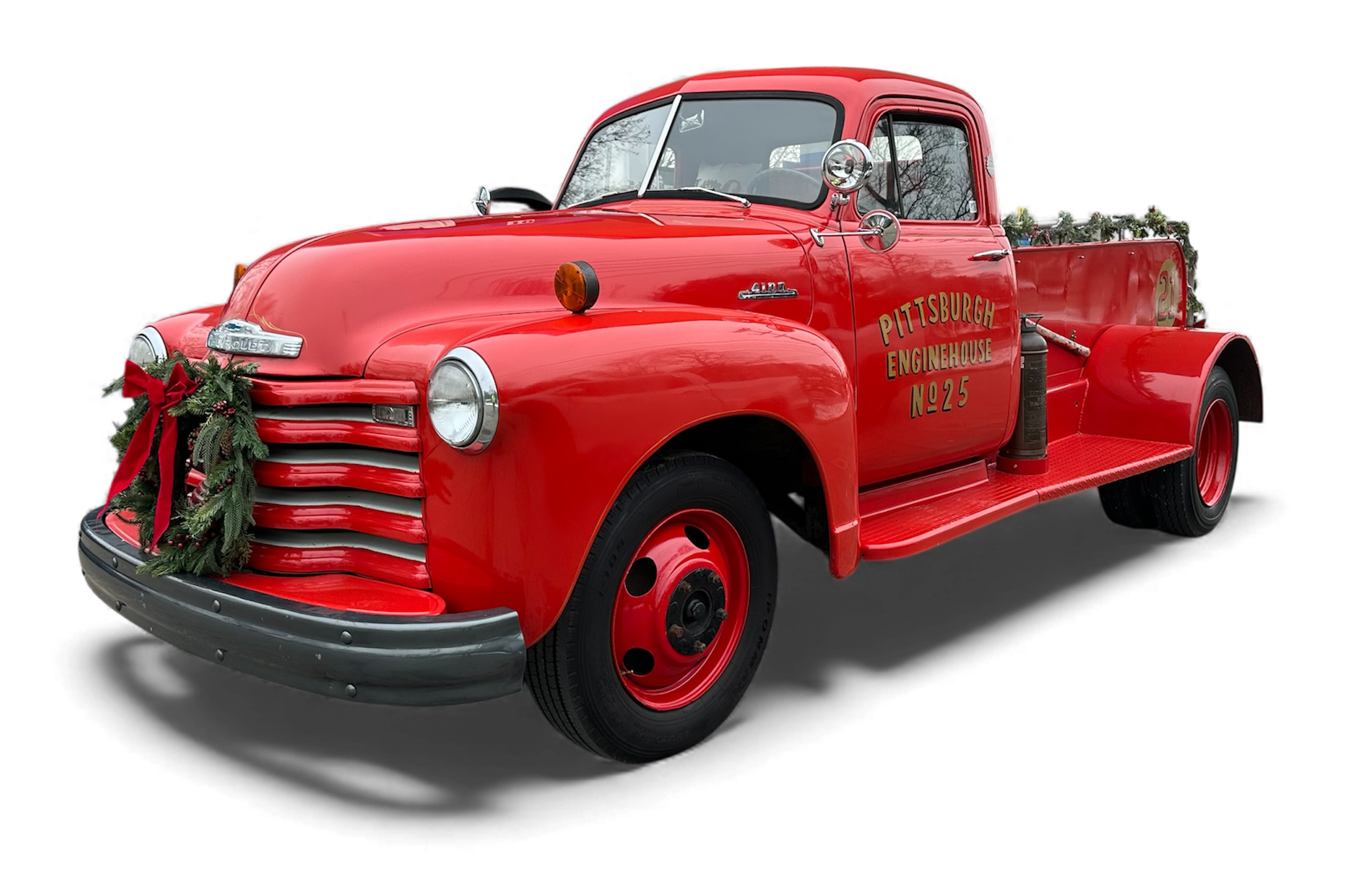 Red vintage fire truck decorated with Christmas greenery and a red bow, with the text "Pittsburgh Enginehouse No. 25" on the door.