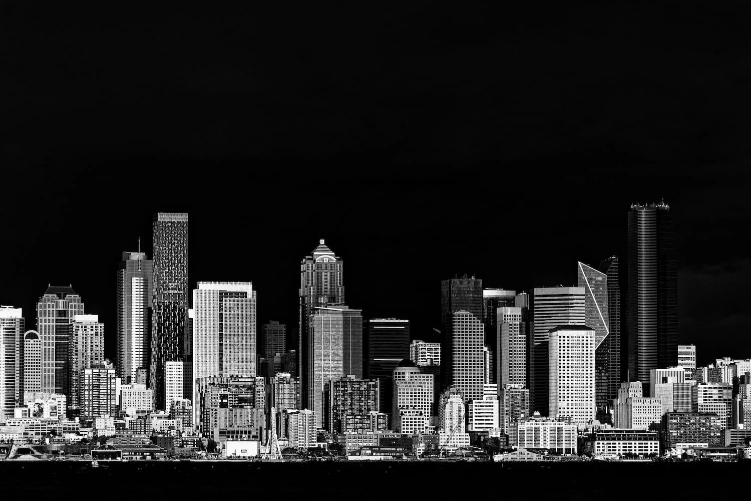 Black and white photo of a city skyline at night with tall skyscrapers and buildings.