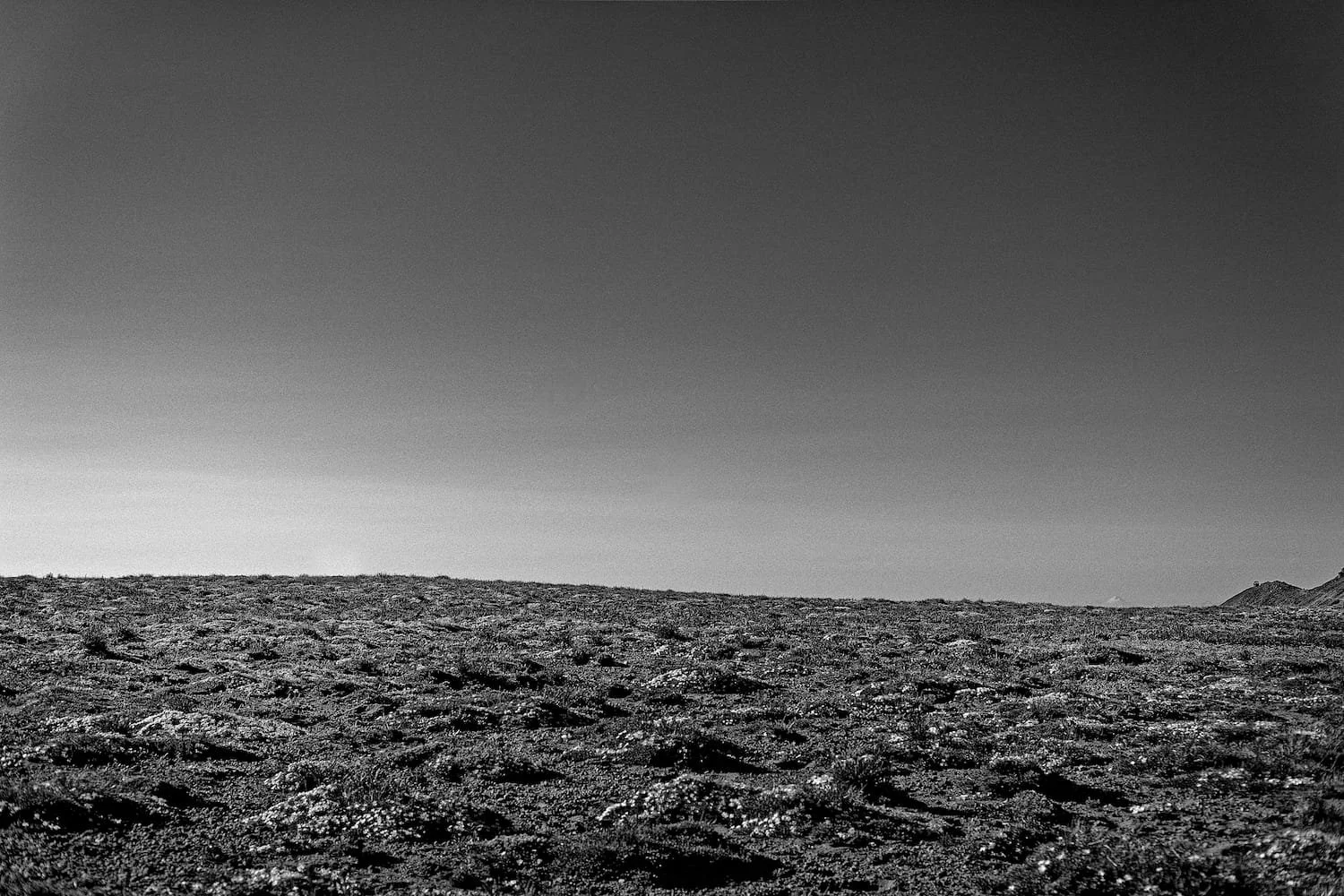 Black and white landscape of a barren rocky terrain with a clear sky in the background.