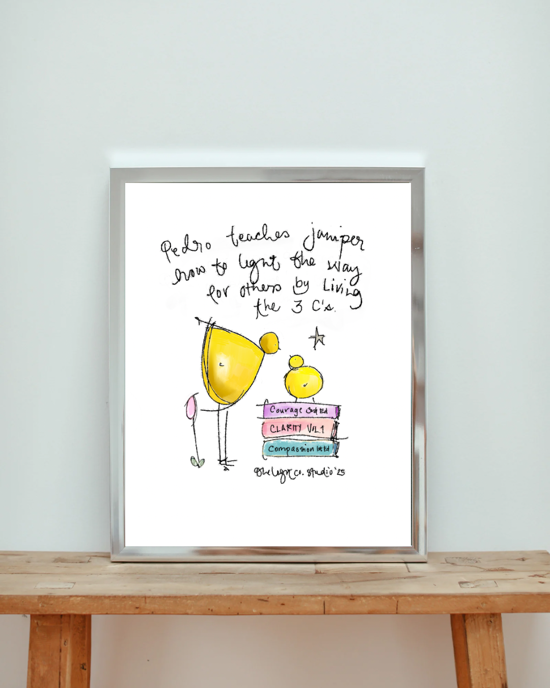 Handwritten note with a colorful illustration of two little chickens and a stack of three books titled "Courage” "Clarity Vol. 1," and "Compassion Ltd." The note says, "Pedro teaches Juniper how to light the way for others by living the 3 C's."