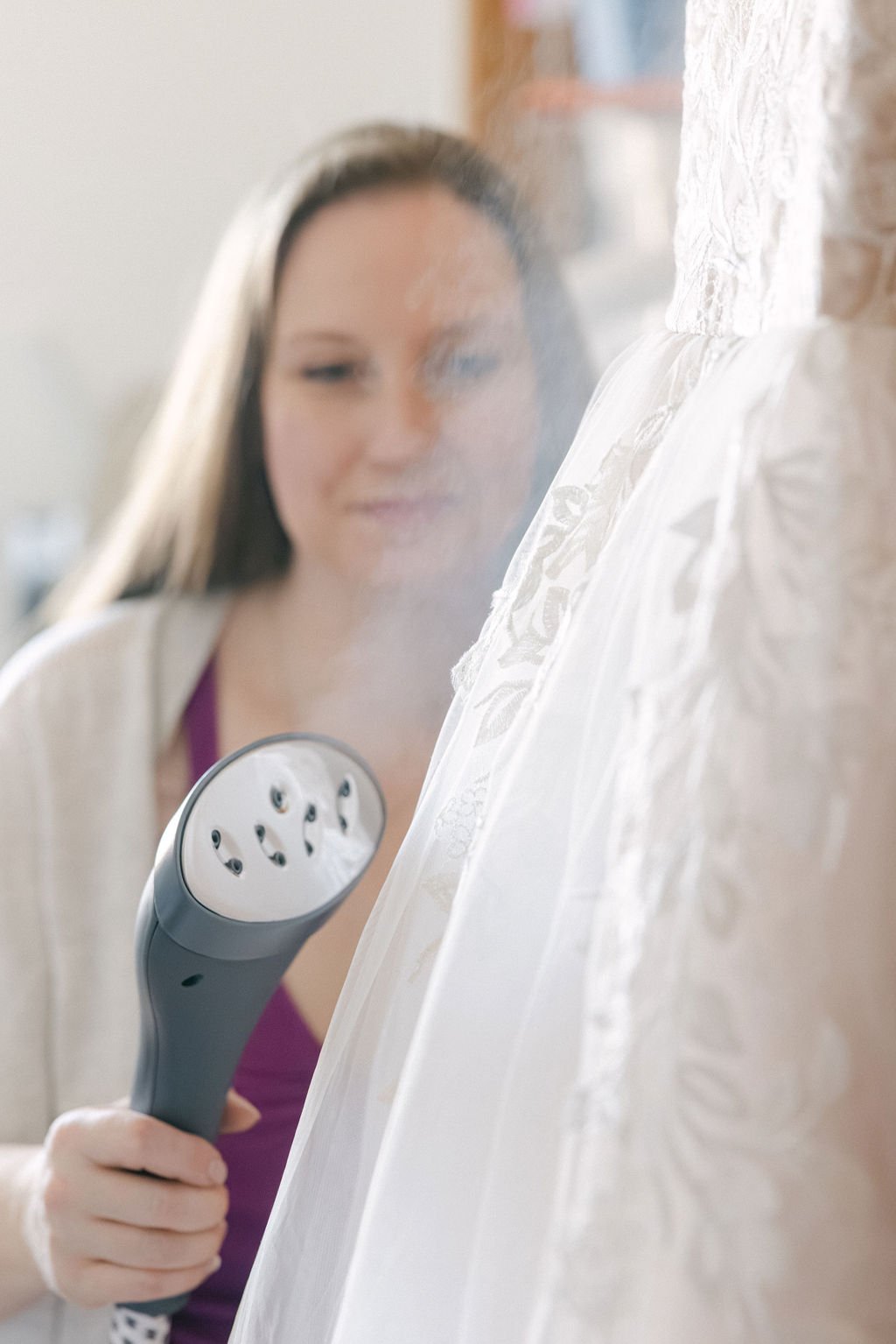 A woman uses a steamer on a lace curtain.
