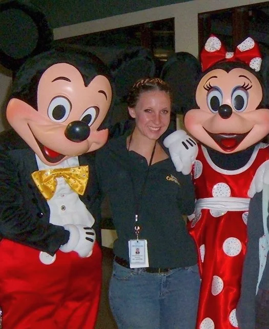 Emily standing between Mickey Mouse and Minnie Mouse characters backstage.
