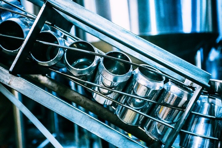 Metal cups stored on a rack in a commercial kitchen.