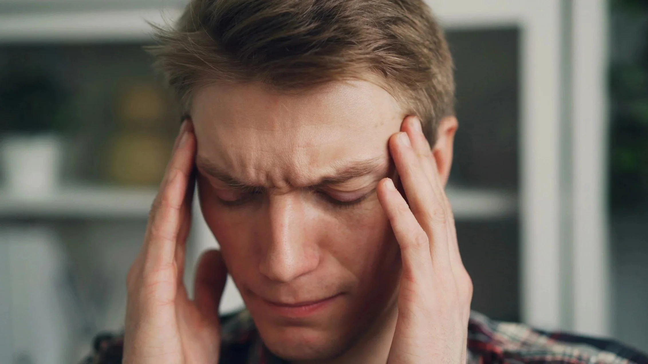 A woman holding her head with both hands with a distressed expression.