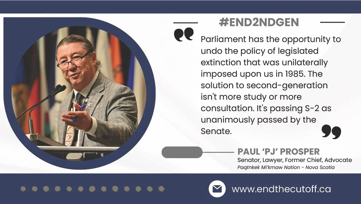 A man in a gray suit and glasses speaking at a podium with flags in the background.