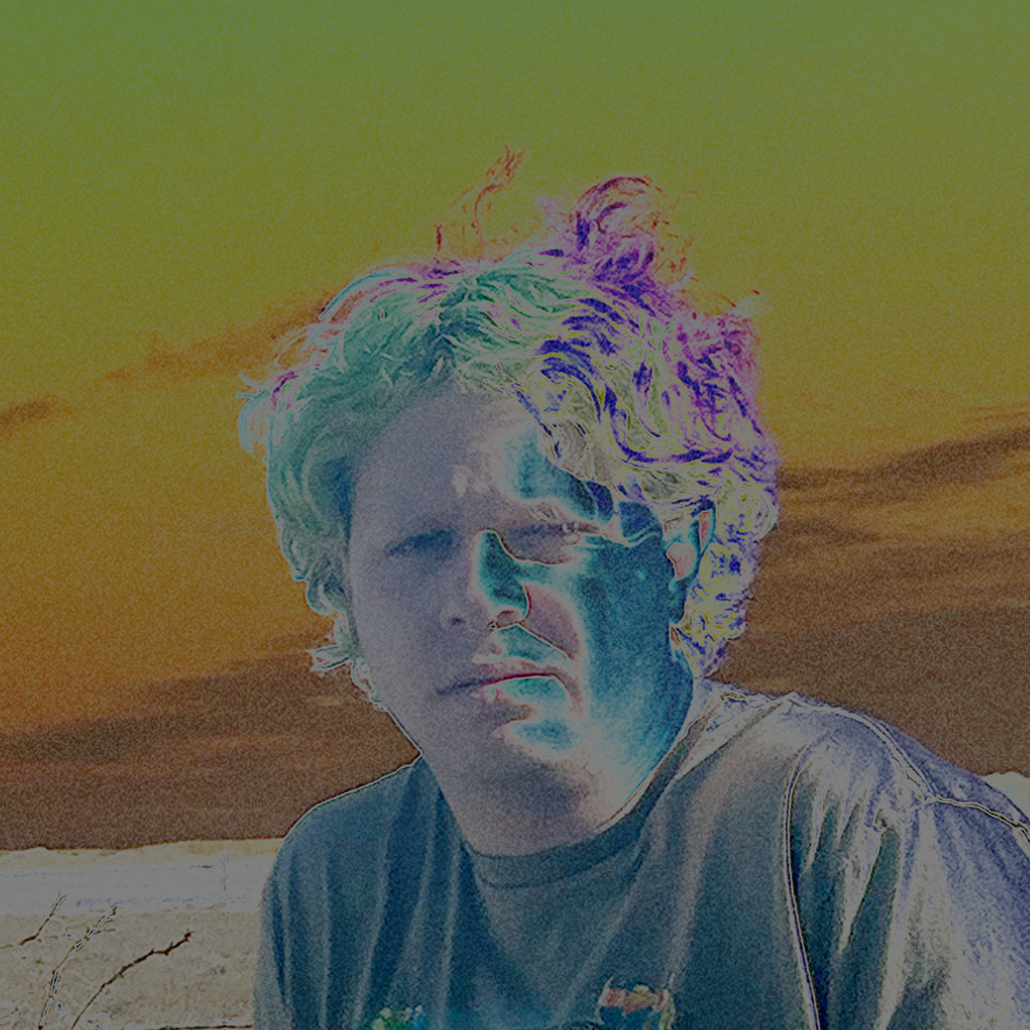 Beam Zillion, with curly hair blowing in the wind, standing in a brown and red desertscape