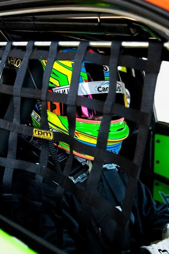 Racing helmet with vibrant geometric patterns inside a vehicle's safety net.