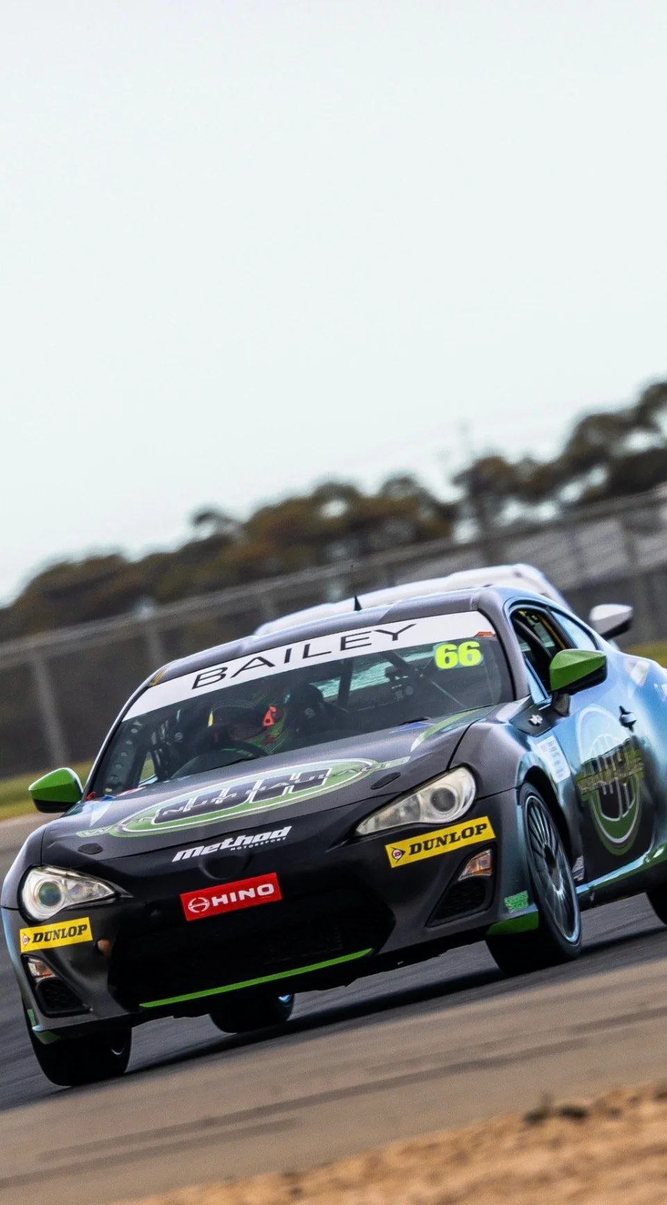 A racing car with the number 66 and the name Bailey on the windshield, on a race track during a race.