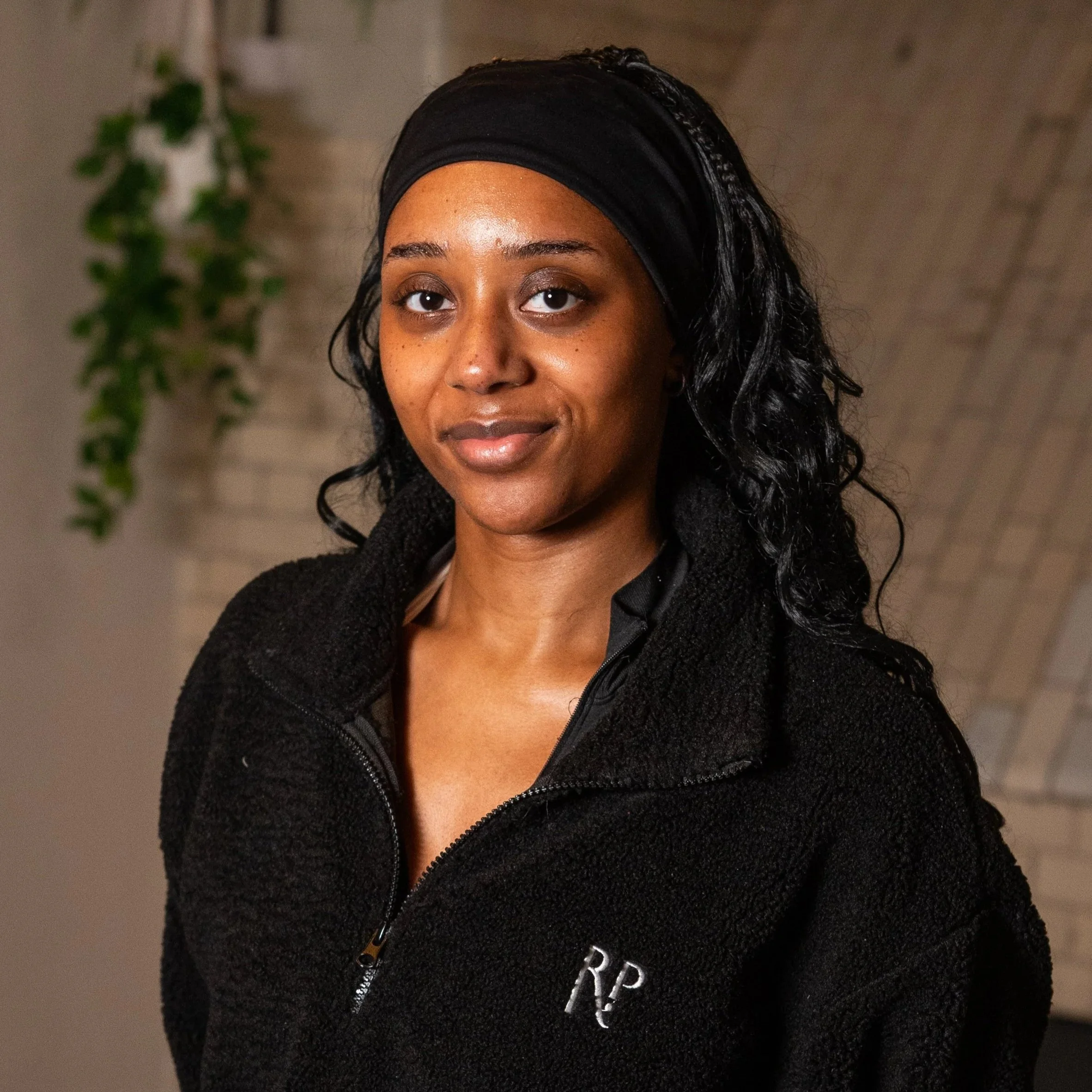 A woman with long black curly hair, wearing a black headband