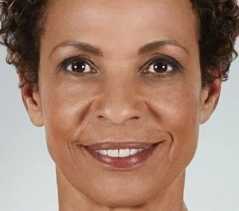 Close-up of a woman with short curly hair smiling at the camera.