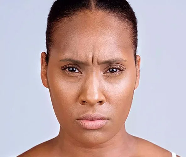 Close-up of a woman with a puzzled or confused expression, furrowing her brow and pursing her lips.