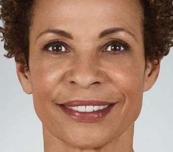 Close-up of a woman with short, curly hair smiling at the camera