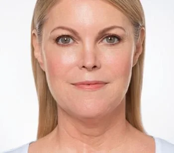 Close-up of a woman with blonde hair and blue eyes, smiling softly against a white background.