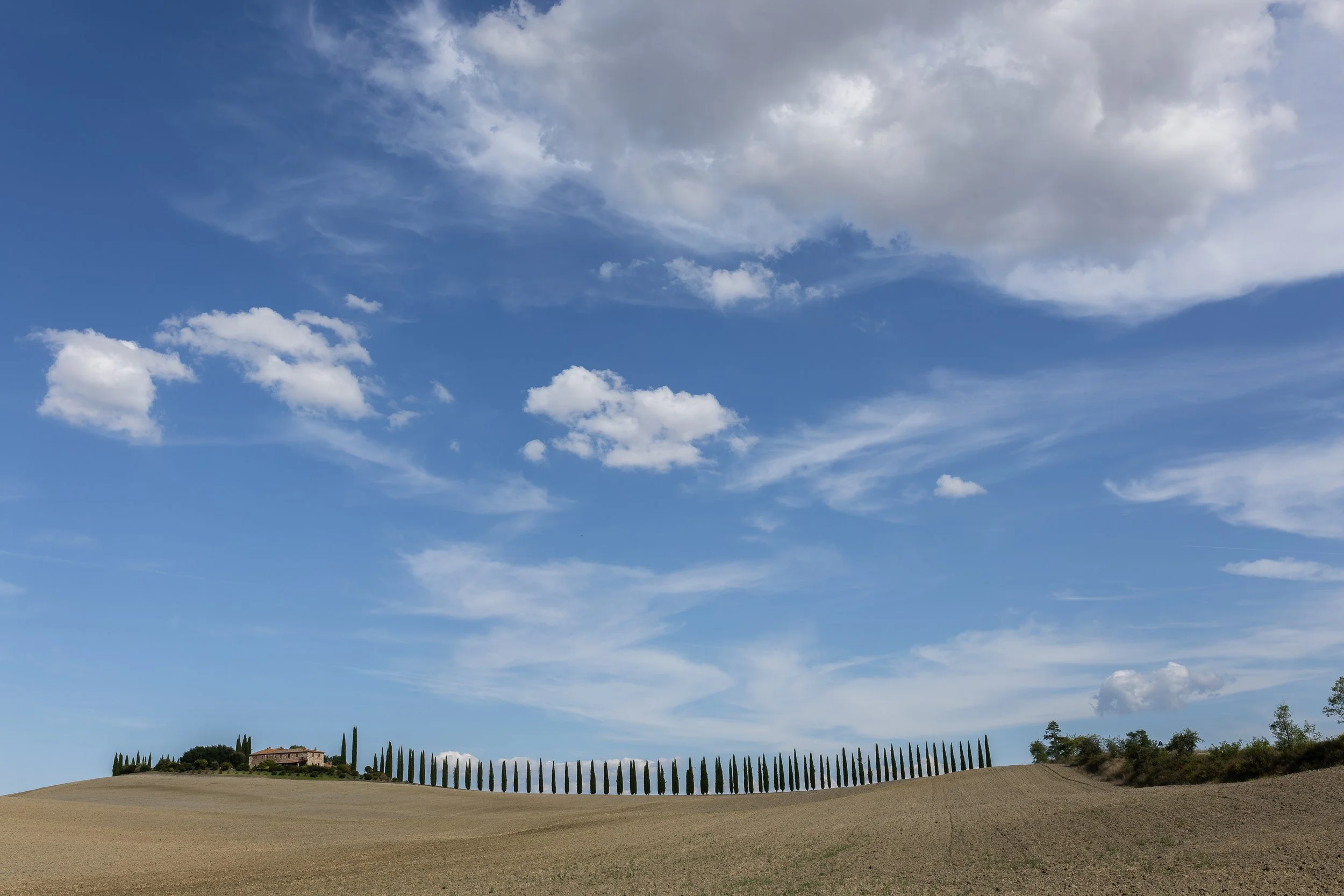 fotografia di paesaggio della Val d'Orcia, agriturismo con cipressi.
