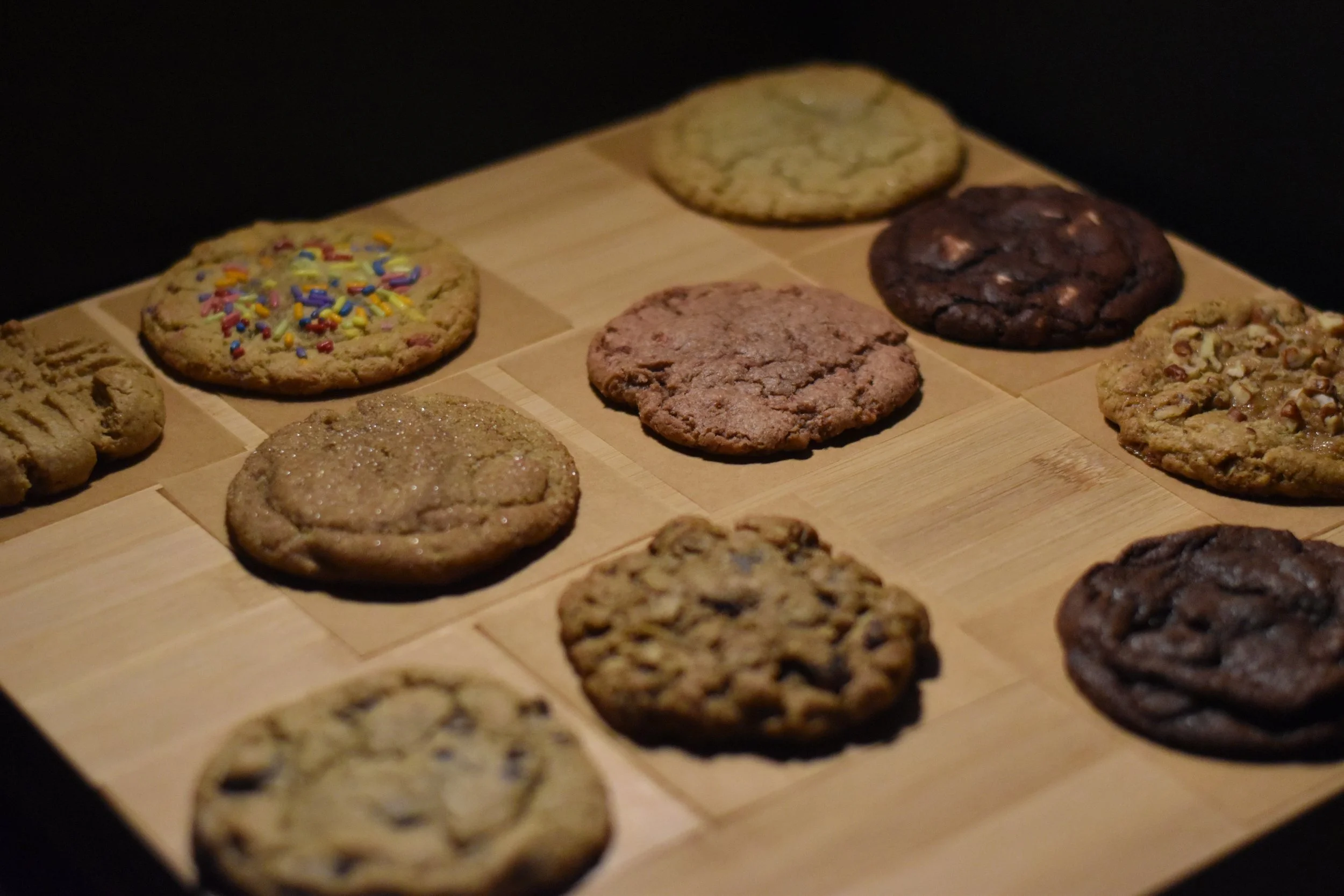 Assorted cookies on a wooden tray, including chocolate chip, sugar, and decorated cookies.