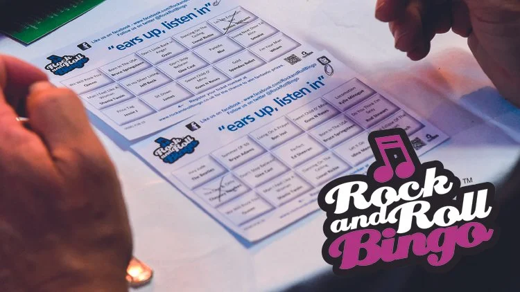 A person playing Rock and Roll Bingo with blank bingo cards on a table.