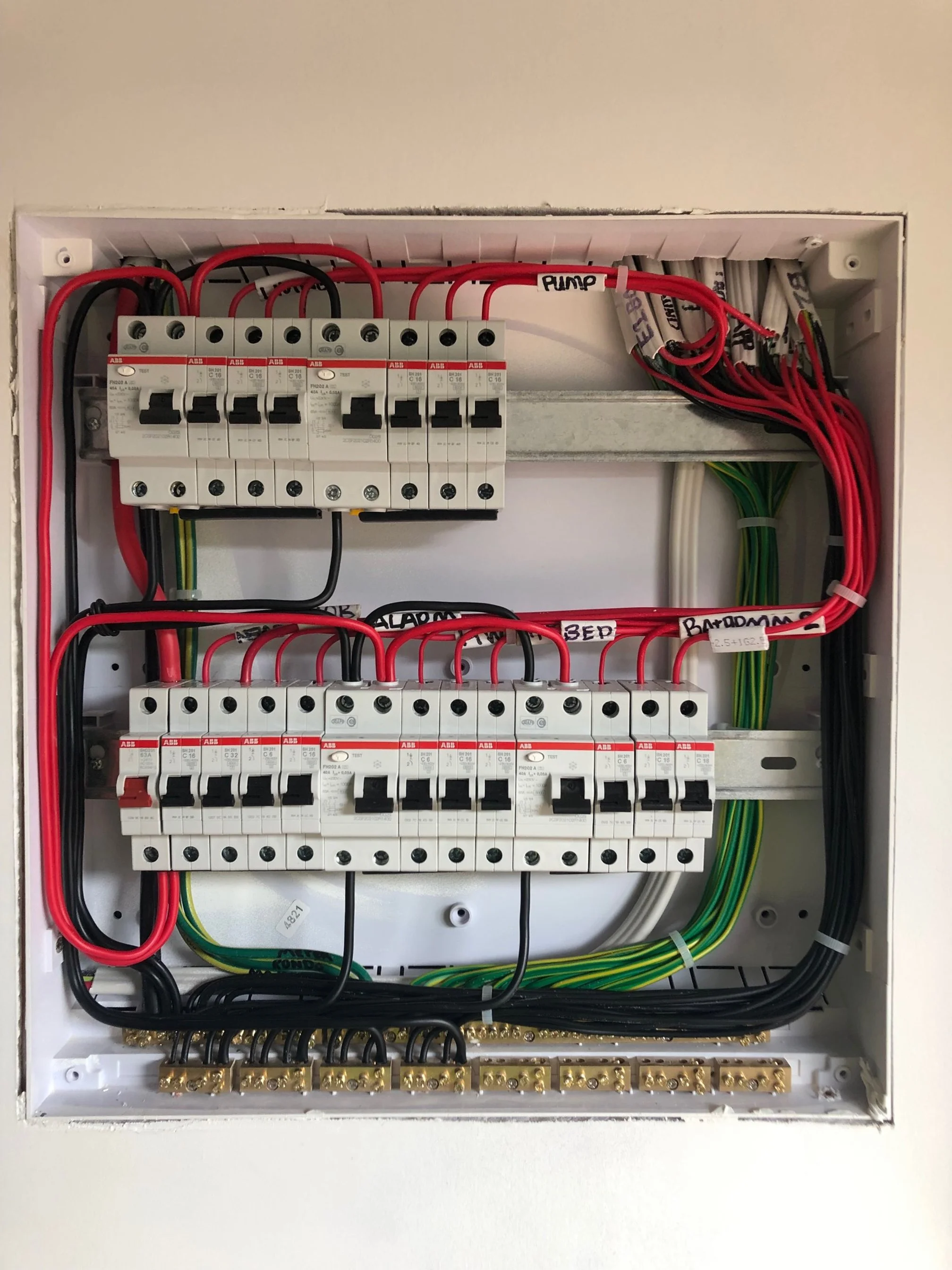 Electrical breaker panel with circuit breakers, wiring, and labels.