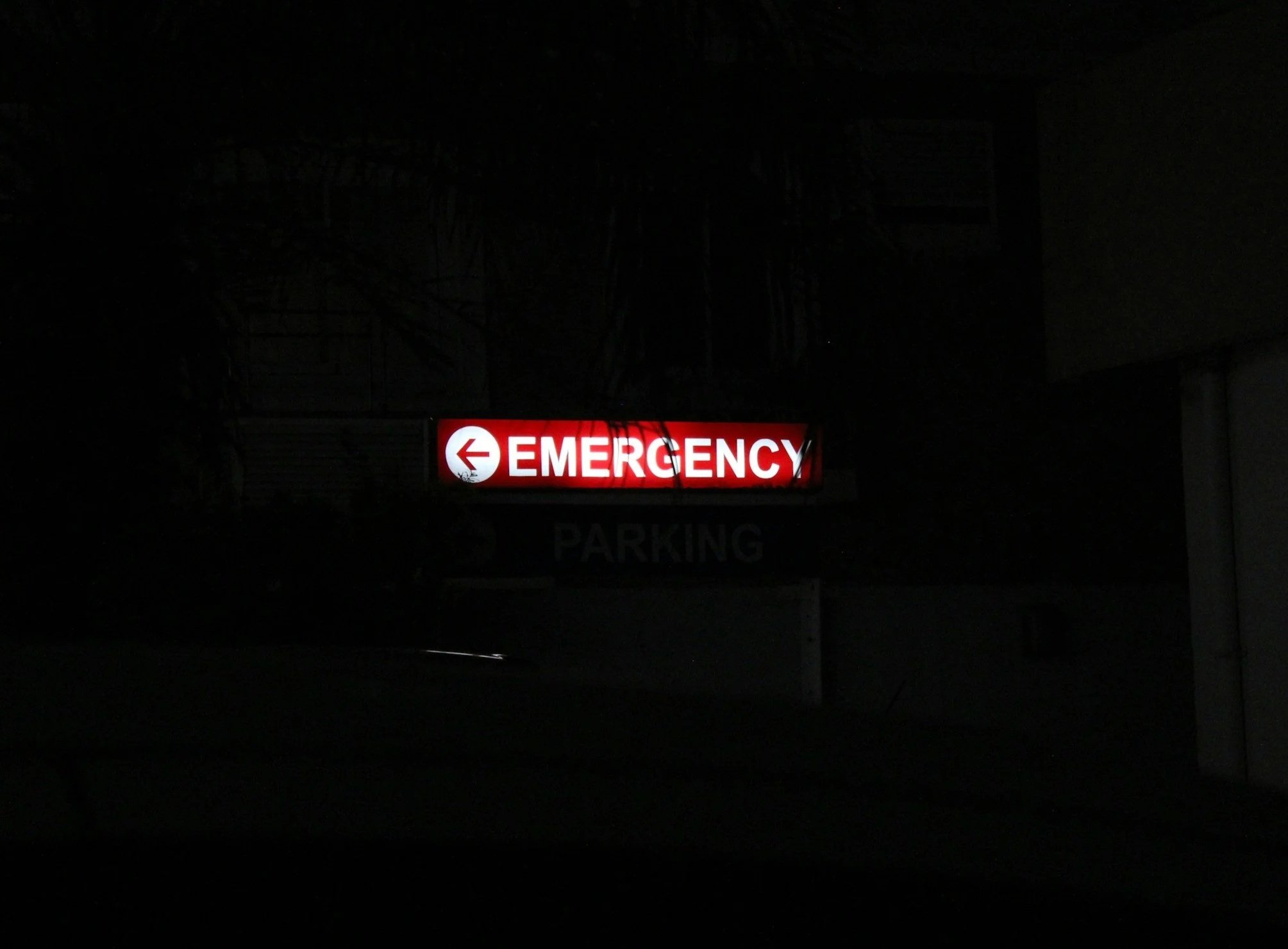 A red illuminated emergency sign with a left arrow on the left and the word 'EMERGENCY' written in white on a dark background.