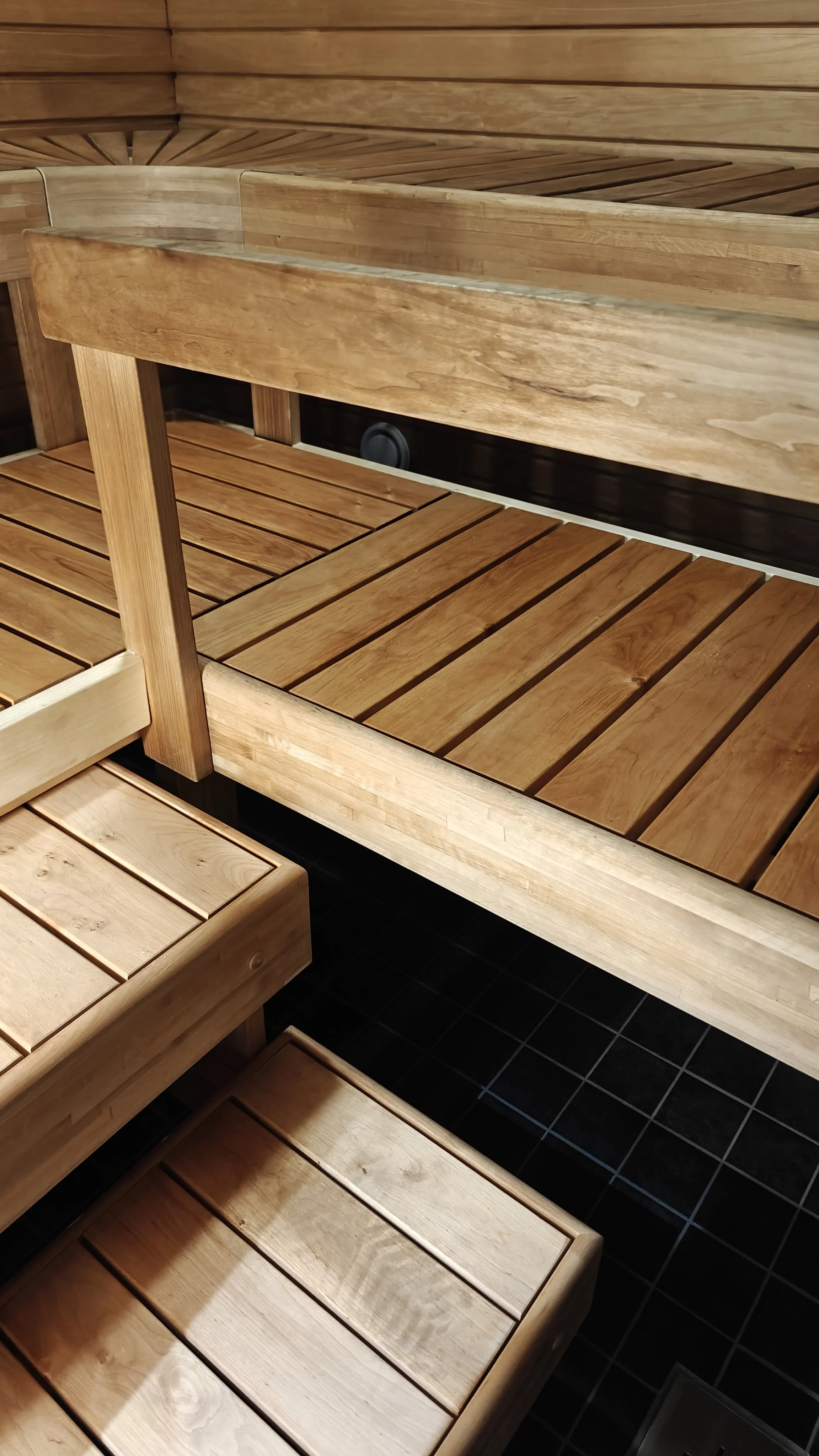Saunan puurakenteisia penkkejä ja lattia, osa seinistä näkyy.