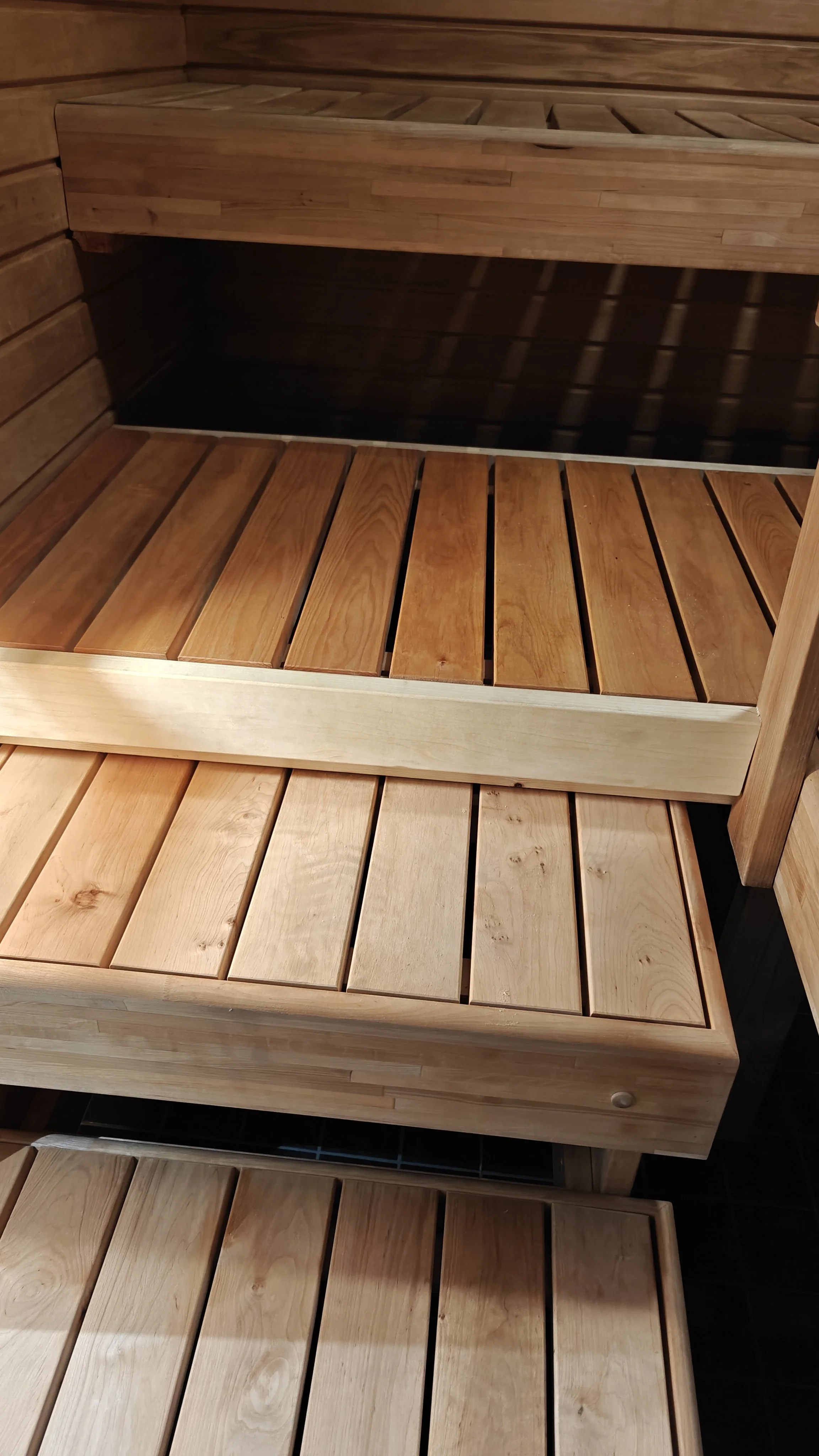 Kolme eriväristä puuräiliötä tai hyllyä, jotka näyttävät olevan osa saunan sisustusta.