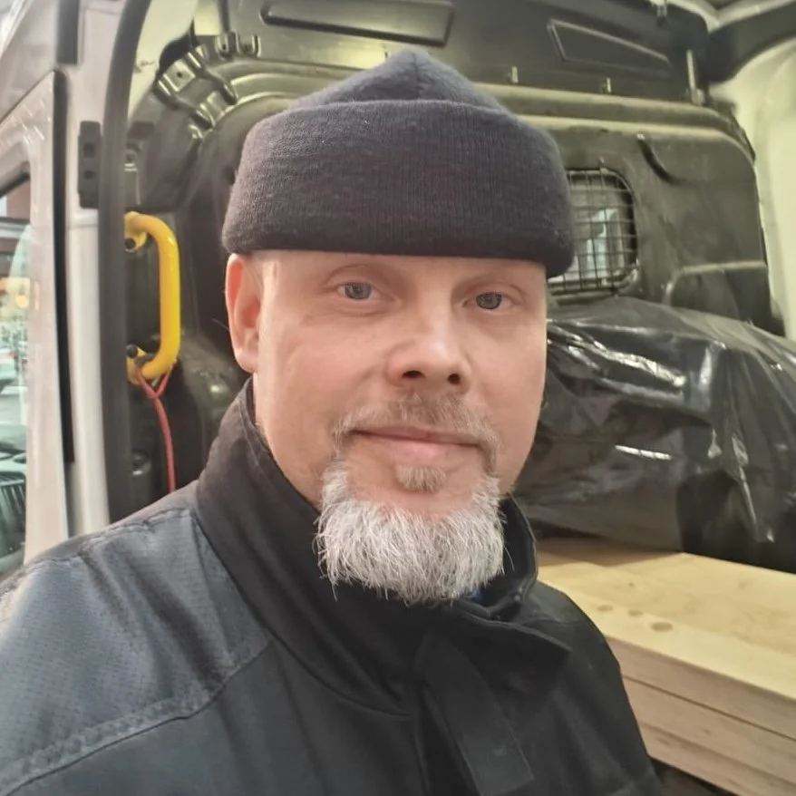 Omistaja, Yrittäjä taustalla auto ja rakennustarvikkeita.