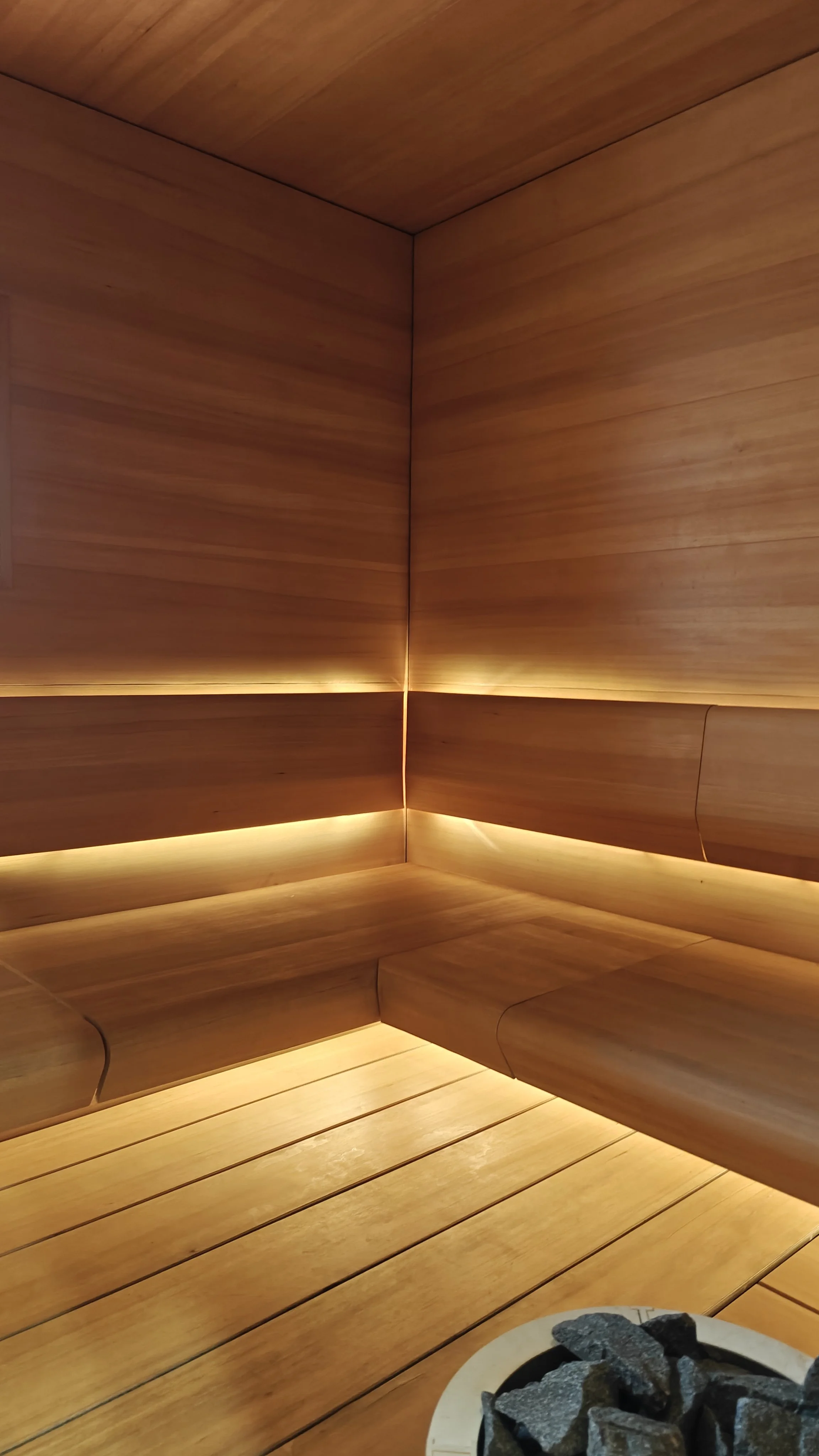 Sauna, seinät ja lattia on puuta, alhaalta näkyvä kiuas.