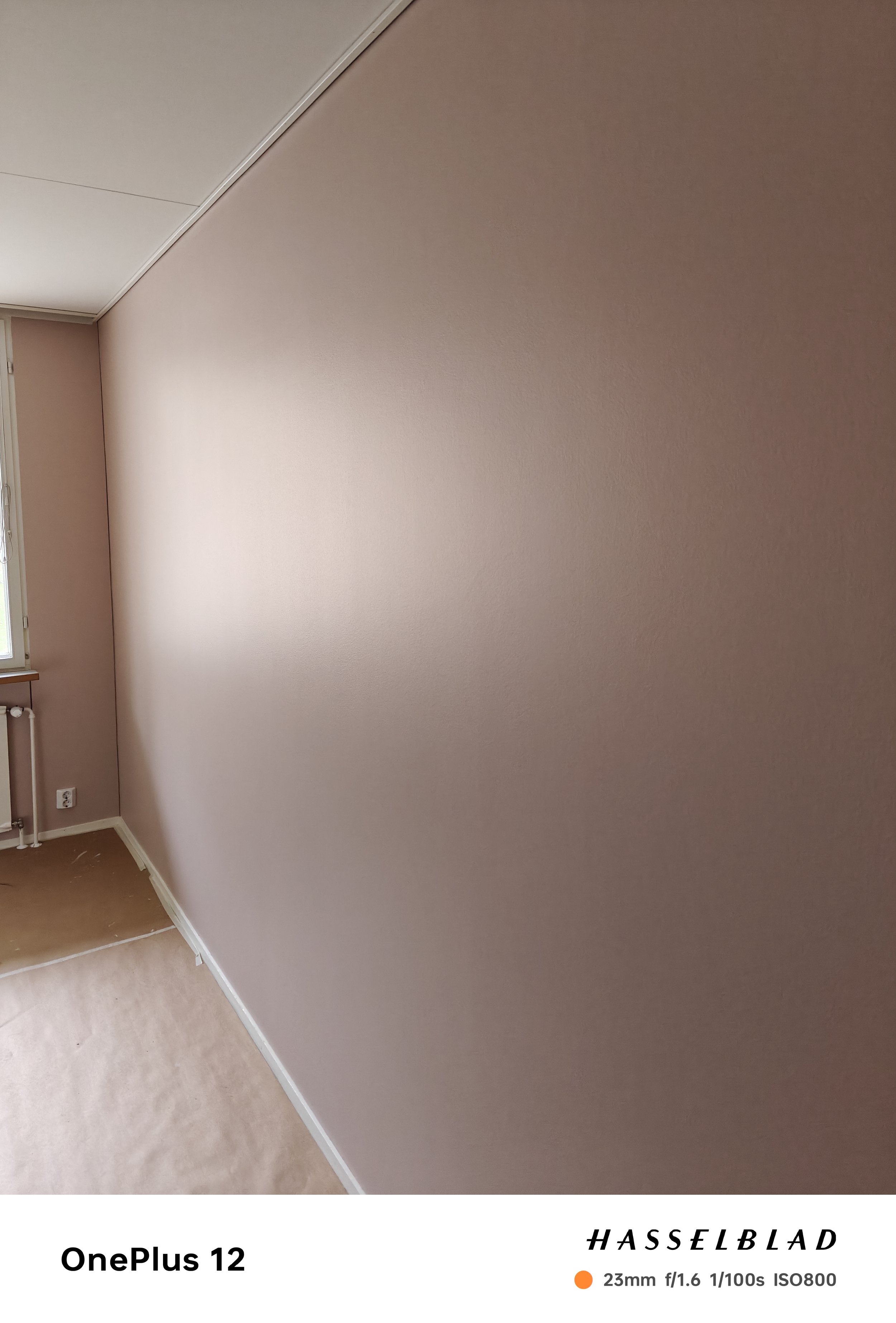 Vaaleanpunainen seinähuoneessa, jossa ikkunan vieressä on sähköpistorasia ja ikkunaluukku