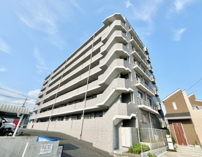 十階建ての白いマンションの建物、青空の下に立っている。