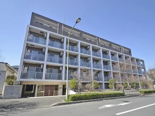 高層のアパートメントビルと道路、街灯、木々が写っている