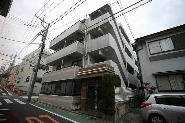 多階建ての白いアパートメントの建物とその周辺の道路と車両の風景