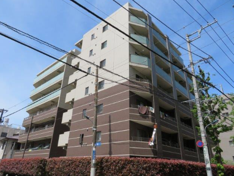 複数階建てのマンションと電線が空に広がる都市の風景