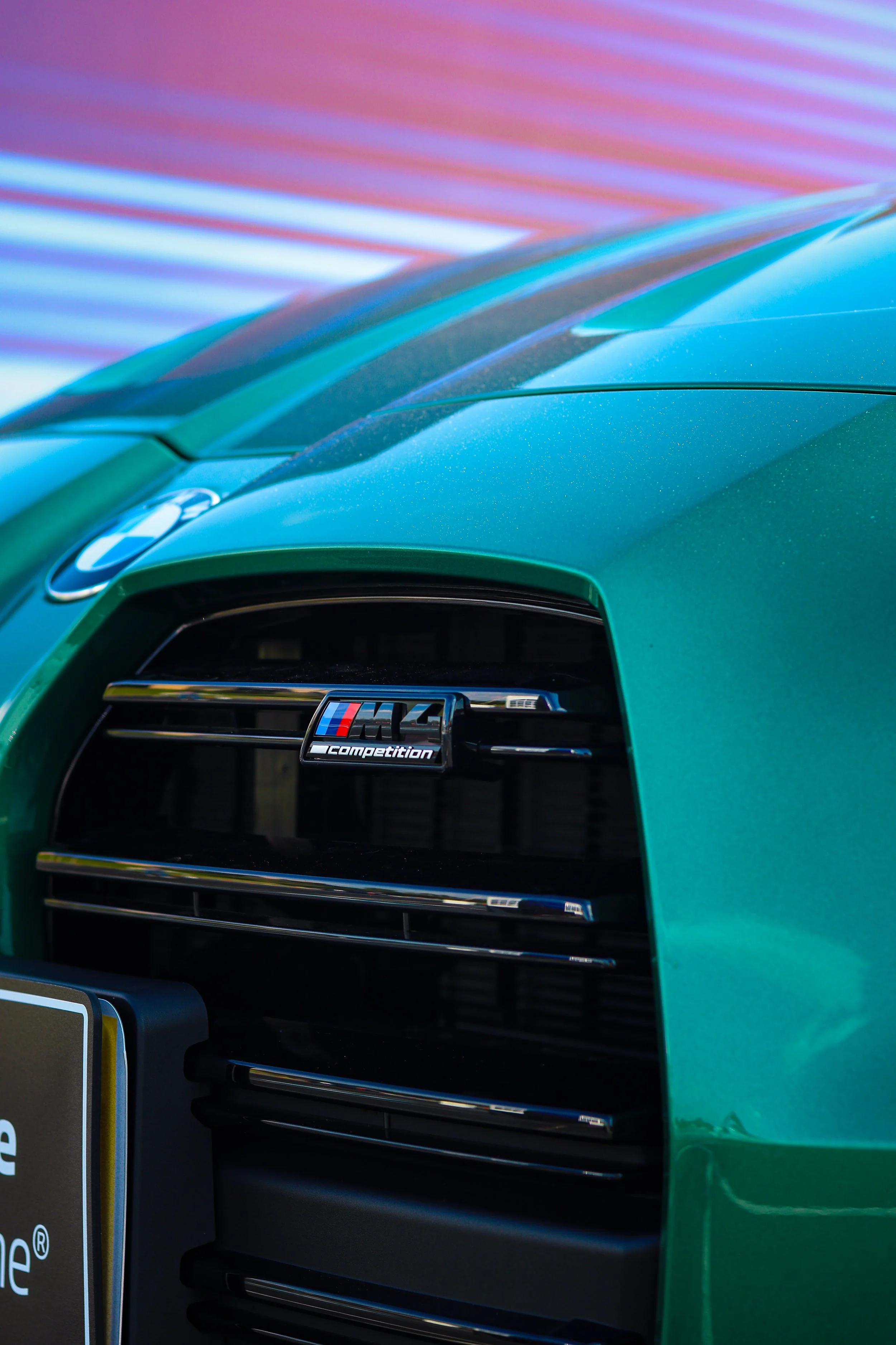 Close-up of the front grille and hood of a green BMW M4 Competition car.