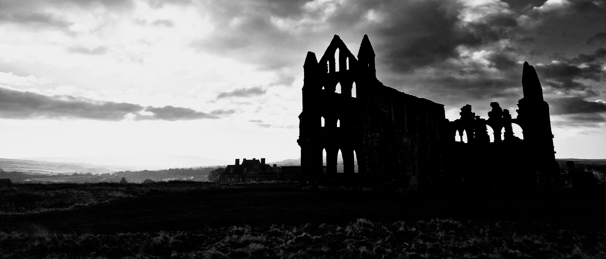 Stoker’s Remains captures the brooding silhouette of a ruined abbey standing defiantly against a storm-laden sky. Shot in sweeping 21:9, the landscape feels almost mythic — a world carved from wind, stone and shadow. The structure rises like a jagged