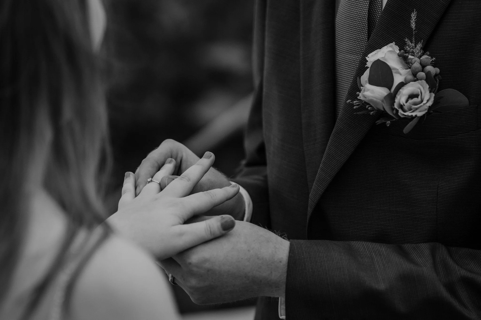 Een close-up van een bruiloft, met een paar dat elkaar vasthoudt, de bruidegom doet de trouwring om bij zijn bruid.