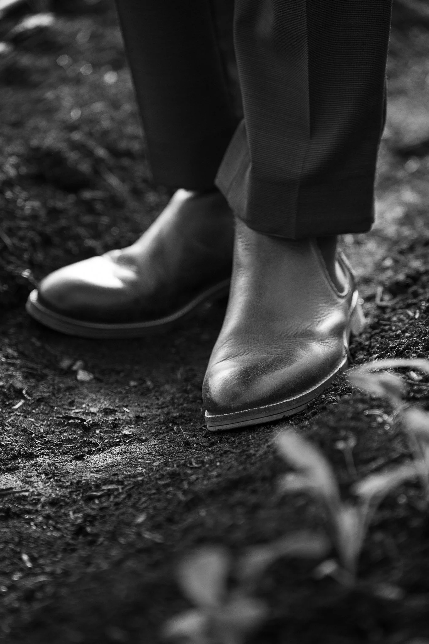 detailfoto van zwarte schoenen en broek van een persoon op de grond.